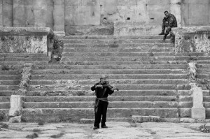 A soldier watches as a fiddler plays a tune in the ruins of Baalbek, Lebanon. A somewhat perfect juxtaposition and incredibly beautiful reminder. (C) Taylor Craig