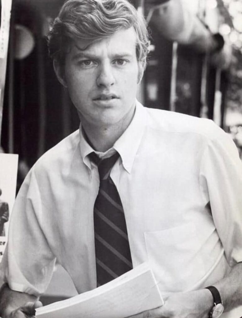 A photo of a young man in tie and holding papers.