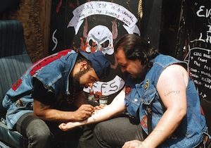 Hand poking a gang member a gang tattoo.